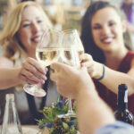 Enjoying Happy Hour at Ruth's Chris Clinking Glasses of White Wine