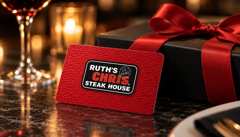 Physical Ruth's Chris gift card displayed on a dark marble counter with a gift box and glass of wine